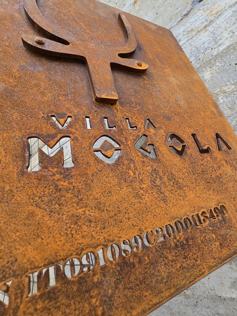 Logo e scritta traforati in una targa in CorTen, da vicino