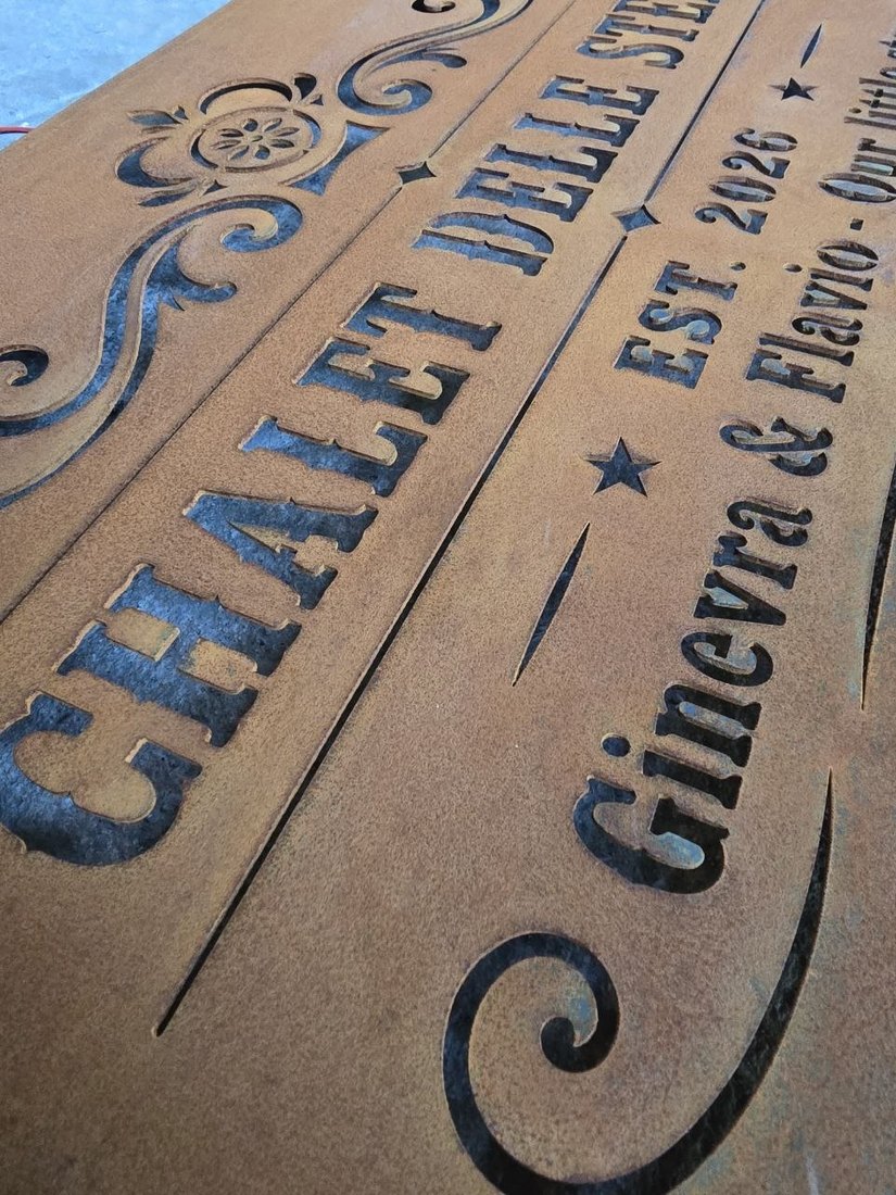 Scritte e volute traforate in un'insegna in CorTen arrugginito