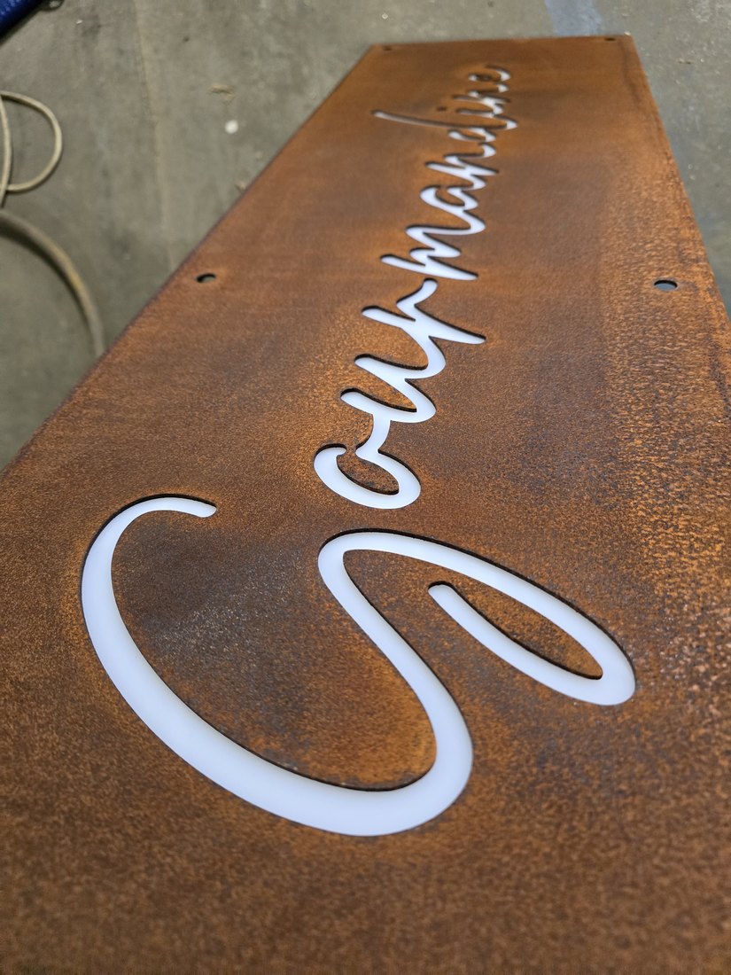 Scritta corsiva traforata nel CorTen con pannello bianco di contrasto